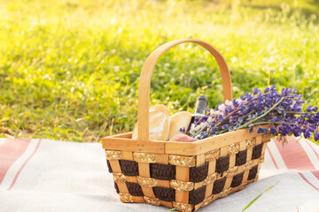 Fototapeta na wymiar Picnic basket with Lupinus, baguette, wine on a tablecloth on a background of green grass