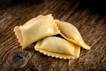 Rectangular classic agnolotti ravioli with filling on a wooden background. Fresh Italian pasta ravioli, rustic style, close-up