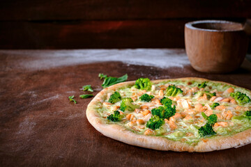 Pizza with broccoli, mozzarella and pesto sauce. Traditional Italian baked pizza on a wooden Table. Close up