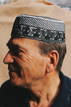 Left side closeup portrait of smiling Turkish Muslim man with Taqiyah / takke : the islamic prayer cap and face wrinkles
