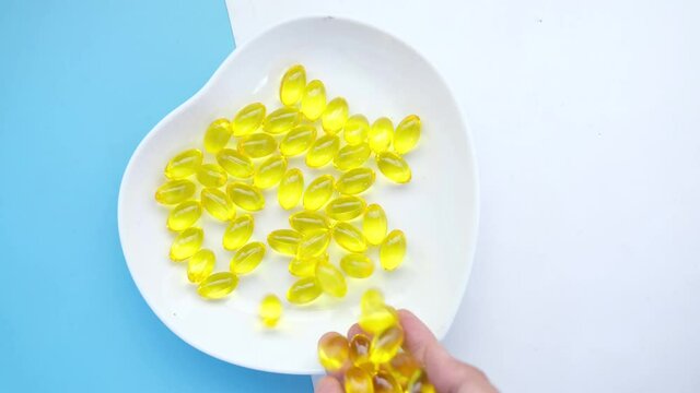 Close up of many vitamin capsule on heart shape plate on color background 