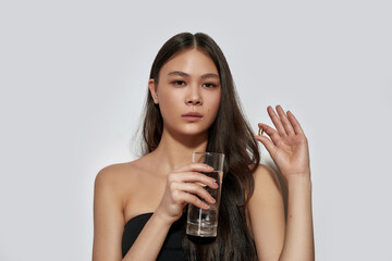 Young asian girl holding pill and glass of water - obrazy, fototapety, plakaty