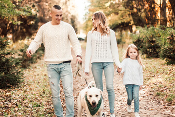 Happy beautiful family with dog labrador is having fun together walking the in park.