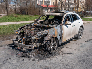 White Burned car at the edge of the road.