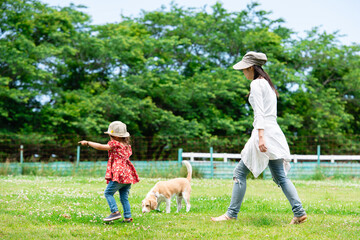 Obraz premium 野原を歩く母と娘と愛犬