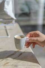 female hands holding a cup of fresh coffee in a bar, morning concept