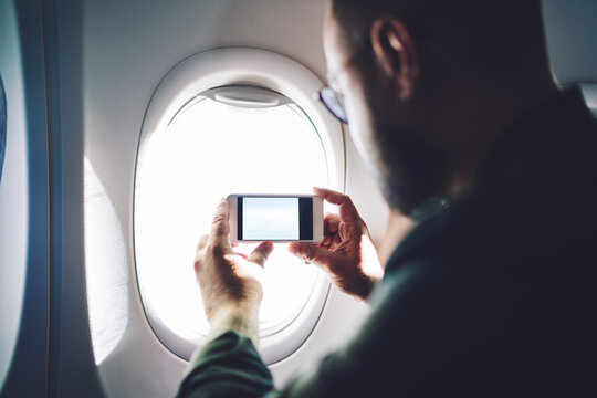 Passenger of airplane taking photo through window
