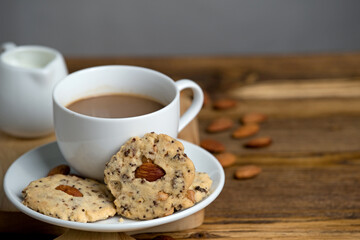 Almond and black sesame butter cookies with milk coffee in white cup on rustic wooden plate and table with copy space.