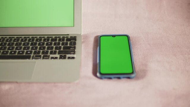 Gros plan d'un Smartphone et d'un ordinateur portable avec &eacute;cran vert sur fond isol&eacute; de couleur blanc casser