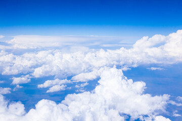 Naklejka na ściany i meble Cumulus white clouds and blue sky from the height of an airplane.