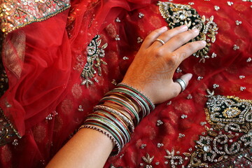 junge Hand mit schönem indischen Schmuck und vielen Amreifen auf rotem Tuch
