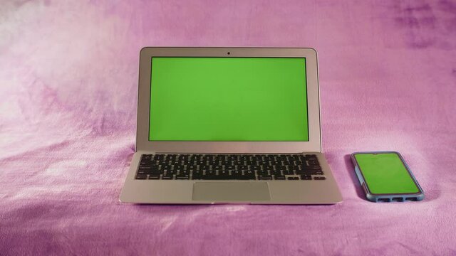 Ordinateur portable et smartphone avec &eacute;cran vert sur fond isol&eacute; de couleur rose
