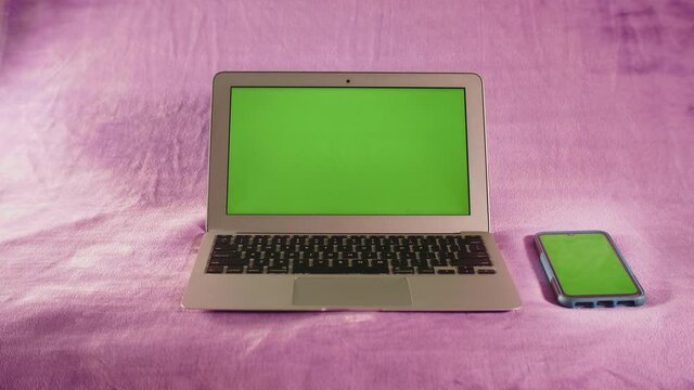 Ordinateur portable et smartphone avec &eacute;cran vert sur fond isol&eacute; de couleur rose