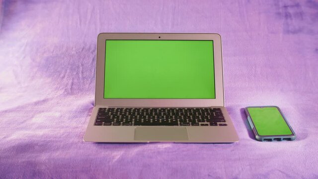 Ordinateur portable et smartphone avec &eacute;cran vert sur fond isol&eacute; de couleur rose