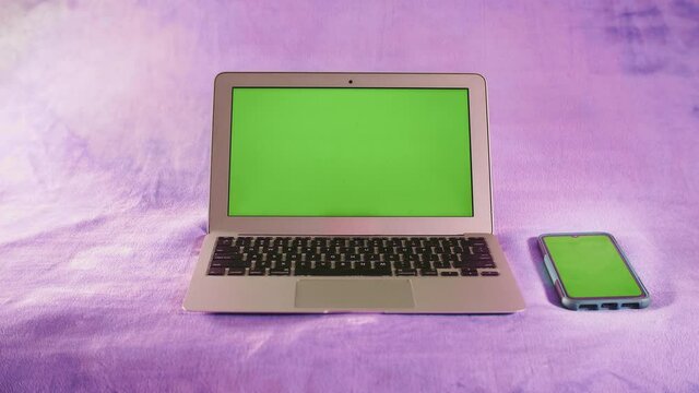 Ordinateur portable et smartphone avec &eacute;cran vert sur fond isol&eacute; de couleur rose