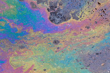 Fototapeta na wymiar Colorful circular iridescent spot of gasoline or oil leakage on the asphalt.