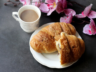 Cup of coffee, croissant and orchids