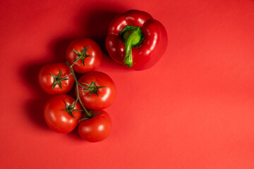 Juicy red vegetables tomatoes and bell peppers on a bright red background. Kitchen. background for restaurant. tomato sprig.