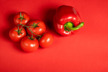 Juicy red vegetables tomatoes and bell peppers on a bright red background. Kitchen. background for restaurant. tomato sprig.