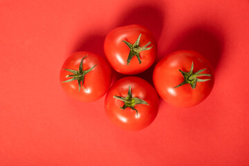 Juicy tomatoes on a bright red background. Fresh vegetables on a branch. Kitchen. background for restaurant.