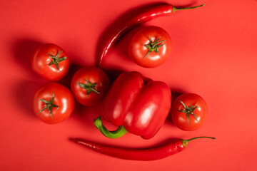 Juicy red vegetables tomatoes and chili peppers and bell peppers on a bright red background. Kitchen. background for restaurant. tomato sprig.
