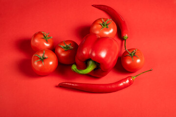 Juicy red vegetables tomatoes and chili peppers and bell peppers on a bright red background. Kitchen. background for restaurant. tomato sprig.