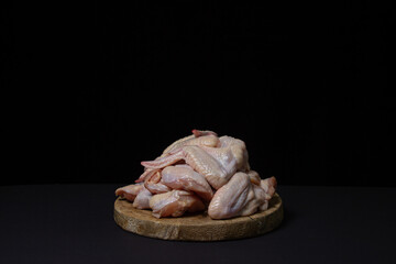 Raw chicken wings on a black background. Fresh chicken meat. Heap of raw chicken wings on a wooden board.