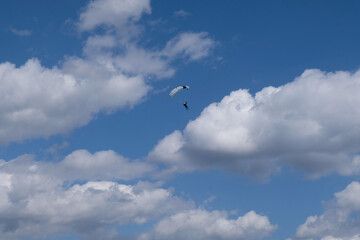 Skydiving. A skydiver is in the cloudy blue sky.