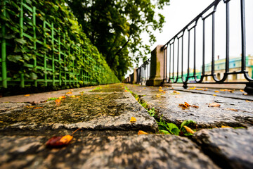 Rainy autumn day in the city, an alley in the park running along the embankment. Wide angle view from the level of granite pavement