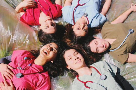Group portrait of doctor / medical student / healthcare worker women smiling and happy outdoors in scrubs with stethoscopes 