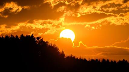 Awesome sunset over the mountains, the sun half covered by a cloud, Germany