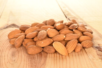 Several grains of peeled raw, organic almonds, close-up, on a wooden table.