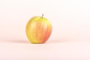 A whole apple on a pale pink background with place for text.