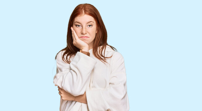 Young read head woman wearing casual sweatshirt thinking looking tired and bored with depression problems with crossed arms.