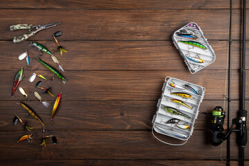 Fishing tackle - fishing spinning rod, hooks and lures on wooden background. Active hobby recreation concept.