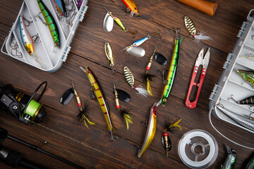 Fishing tackle - fishing spinning rod, hooks and lures on wooden background. Active hobby...