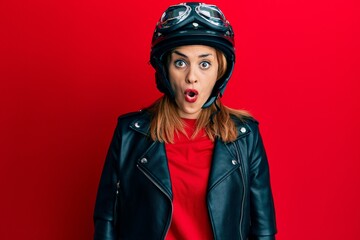 Hispanic young woman wearing motorcycle helmet scared and amazed with open mouth for surprise, disbelief face