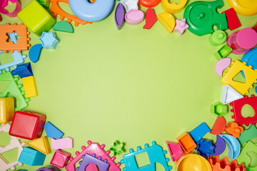 Fototapeta na wymiar Childrens toys, blocks and puzzles on a green background top view. Preschool education.