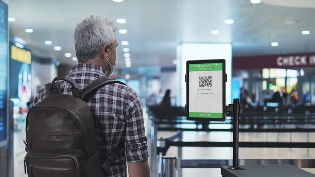 man showing covid-19 vaccination certificate at the airport security check,male tourist shows coronavirus digital vaccine passport at the departure control area,travel safety measures
