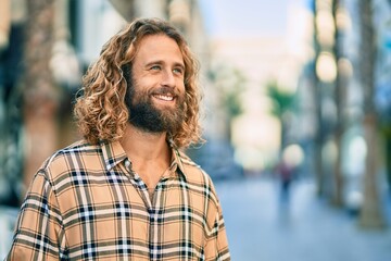 Young caucasian man with long hair smiling happy at the city.
