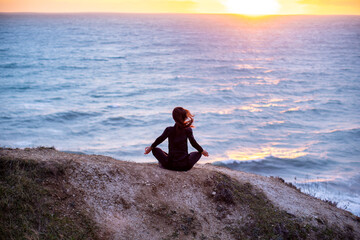 Woman meditating and doing youga at sunset