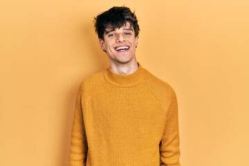 Handsome hipster young man wearing casual yellow sweater with a happy and cool smile on face. lucky person.