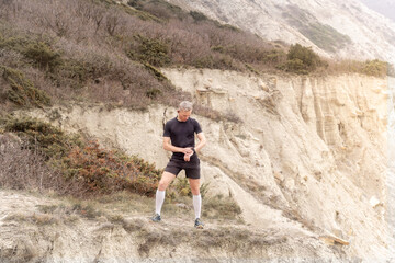 Runner standing on mountain, looking on watch