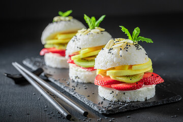 Sweet sush burger with fresh tropical fruits on stone plate.
