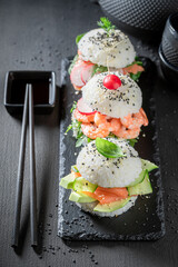 Delicious sush burger with seafood and vegetables sprinkled with sesame.