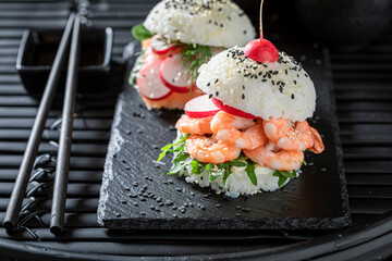 Tasty sush burger with rice and seafood sprinkled with sesame.