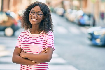 Young african american girl with arms crossed smiling happy standing at the city.