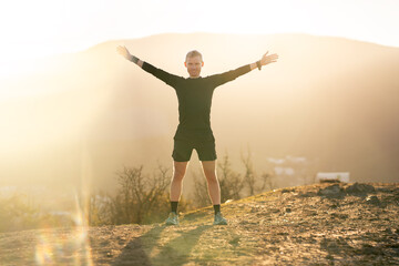 Man standing, smiling with sunrise in mountains