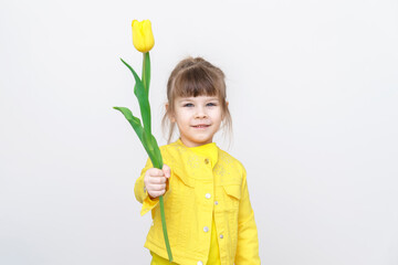 cute caucasian child girl in yellow clothes with yellow tulip