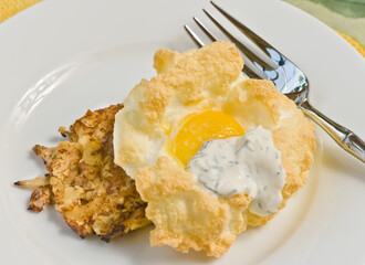 top view, close up of baked egg over a fried crusted crab meat, on a round, white plate     